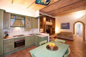 una cucina con armadi verdi, tavolo e divano di Casa Siena Vallepiatta a Siena