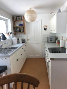 a white kitchen with a sink and a stove at Tremanhire Cottage in Solva