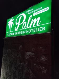 a green sign for a palin hotel on a brick wall at Palm Rezidential in Sebeş