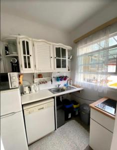 a small kitchen with white cabinets and a sink at Pipacs in Balatonszárszó