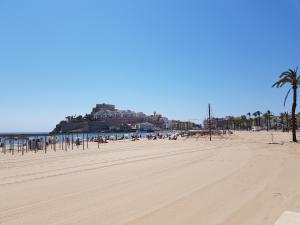 PEÑISCOLA PLAYA al lado del hotel papa Luna في بينييسكولا: اطلالة على شاطئ مع قلعة في الخلفية