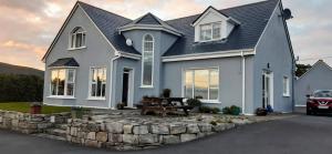 a blue house with a stone retaining wall at Creevagh (Room Only) in Keel +37 photos