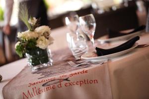 a table with wine glasses and a vase with flowers on it at Hotel Restaurant de la Tour in Sanary-sur-Mer