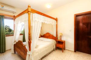 a bedroom with a canopy bed and a window at Follow The Sun Hotel Apartments in Polis Chrysochous