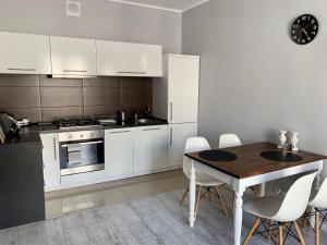 a kitchen with white cabinets and a table with chairs at Apartament Abrahama 40 in Gdynia
