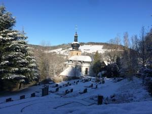 a church in the snow with a cross on top at Pension Bahnmeister in Probstzella