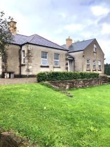 una antigua casa de ladrillo con un gran patio en Grannan School, Trillick, Fermanagh and Omagh, Tyrone, en Trillick
