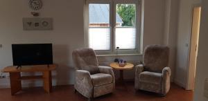 salon z 2 krzesłami, telewizorem i stołem w obiekcie Großzügige Wohnung in Mecklenburg zwischen Wald und Seen w mieście Krakow am See