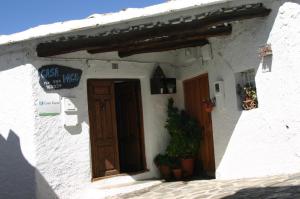 a white building with a door and a sign on it at Apartamentos y Casas Rurales Las Terrazas de la Alpujarra in Bubión