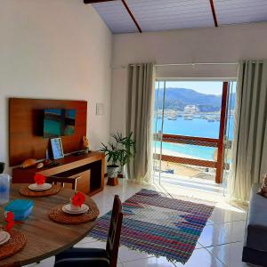 a living room with a table and a view of the ocean at Bela Vista Flats in Arraial do Cabo