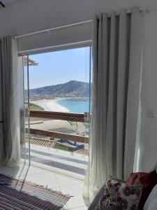 a room with a window with a view of a beach at Bela Vista Flats in Arraial do Cabo