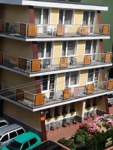 ein Apartmenthaus mit Balkonen, Tischen und Stühlen in der Unterkunft pokoje STIFADO in Misdroy