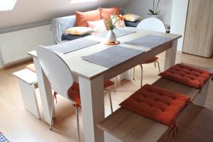 mesa de comedor blanca con sillas naranjas y sofá en Apartma Vrh en Lesce