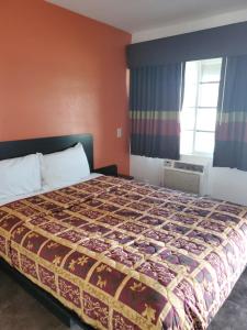 a bedroom with a bed with a bedspread on it at High Desert Inn in Hesperia