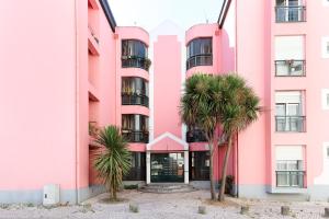 a pink building with palm trees in front of it at Cosy Guesthouse - Sónias Houses in Lisbon