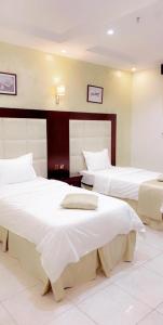 Habitación de hotel con 2 camas con sábanas blancas en Aseel Furnished Apartments, en Yeda