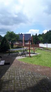 einen Park mit zwei Picknicktischen und einem Spielplatz in der Unterkunft Dom w Gaju nad jeziorem Dębno in Łąkorz