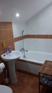 ein Badezimmer mit einem Waschbecken und einer Badewanne mit einem Waschbecken in der Unterkunft Dom w Gaju nad jeziorem Dębno in Łąkorz