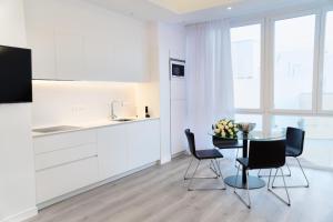 a white kitchen with a table and chairs and a counter at Lauser City Suites in Los Llanos de Aridane