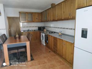 eine Küche mit Holzschränken, einem Tisch und einem Kühlschrank in der Unterkunft Retiro do Caçador in Reguengos de Monsaraz