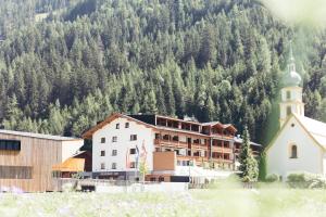 ein Gebäude mit einer Kirche vor einem Berg in der Unterkunft Hotel Kirchenwirt in Kaunertal