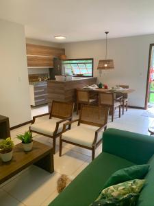 a living room with a couch and chairs and a kitchen at Resort Villas do Pratagy in Maceió
