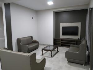 a living room with two chairs and a flat screen tv at Sleep Hotel Assis in Assis Chateaubriand
