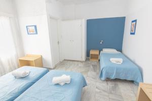 three beds in a room with blue walls at Carlos Pension in Akrotiri