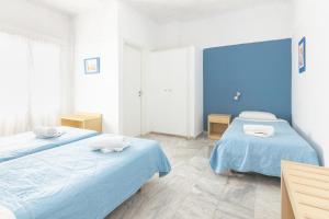 two beds in a room with blue walls at Carlos Pension in Akrotiri