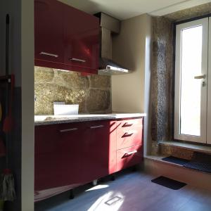 a kitchen with red cabinets and a window at Turismo Rural Macieira Brava in Guarda