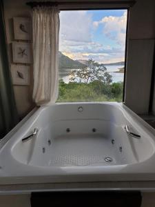 uma banheira na casa de banho com uma grande janela em Casas da Paty em Santana do Riacho