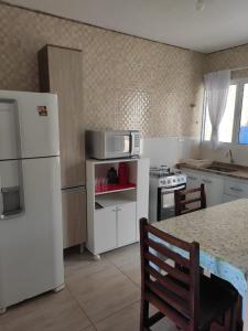 a kitchen with a white refrigerator and a table at Sarau's Beach House Boracéia in Boracéia