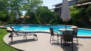 a table with chairs and an umbrella next to a pool at Imbassai - Casa Alto Padrão completa - Condominio Fechado - A1B1 in Imbassai