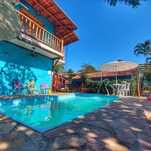 a house with a swimming pool and an umbrella at Espaço Dona Florinha in Ilhabela