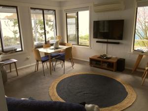 sala de estar con TV, mesa y sillas en 970 Adventure Bay Road, en Adventure Bay