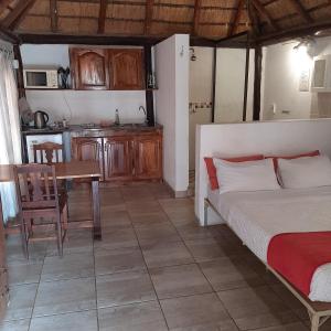 a bedroom with a bed and a table and a kitchen at Karibu River Retreat in Marble Hall
