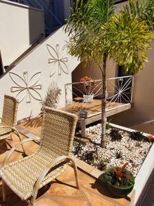 une terrasse avec 2 chaises, une table et des arbres dans l'établissement Hotel Magnólia, à São João da Boa Vista