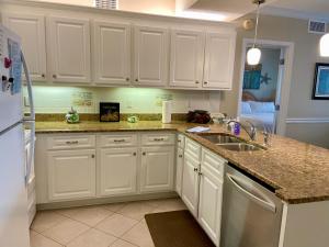 una cocina con armarios blancos y fregadero en Shoalwater 704 en Orange Beach