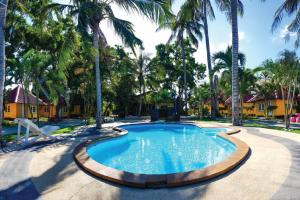 a swimming pool with palm trees in a yard at ริมระเบียงทะเล รีสอร์ท in Phetchaburi