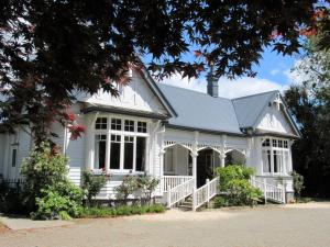 a white house with a gambrel roof at White Elephant Accomodation in Motueka