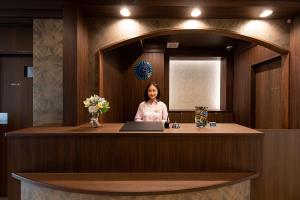a woman standing at a reception desk with a laptop at Stay SAKURA Tokyo ASAKUSA ART DECO HOTEL in Tokyo