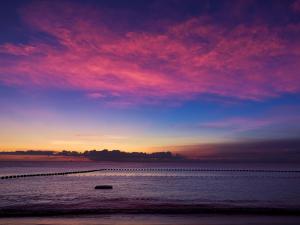 een zonsondergang op het strand met een boot in het water bij The Moon Beach Museum Resort in Onna