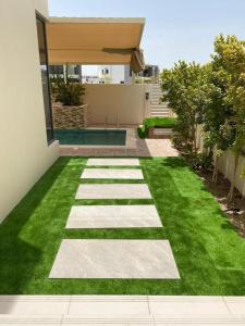 un jardín con césped y una pasarela frente a una casa en 5 bedroom Villa - Dubai Hills en Dubái