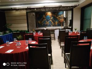 uma sala de jantar com mesas e cadeiras vermelhas e um ecrã em Tarawade Clarks Inn Pune em Pune