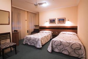 una habitación de hotel con 2 camas y una silla en Hotel Castilla en Gijón
