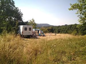 an rv parked in a field of tall grass at Camping La Forêt du Morvan in Larochemillay