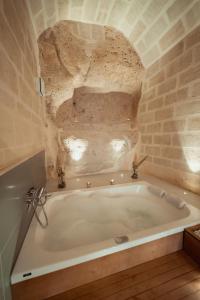 una vasca da bagno in una camera con parete in pietra di Endea Suite Rooms & Lounge SPA a Matera