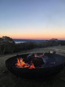 a fire pit in the grass with the sunset in the background at Altitude 1260 in Jindabyne