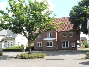 a large brick building with a tree in front of it at Gästehaus Haalck in Weddingstedt