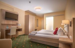 a hotel room with a bed and a desk and a television at Hotel Garni Zur Alten Post in Lembruch